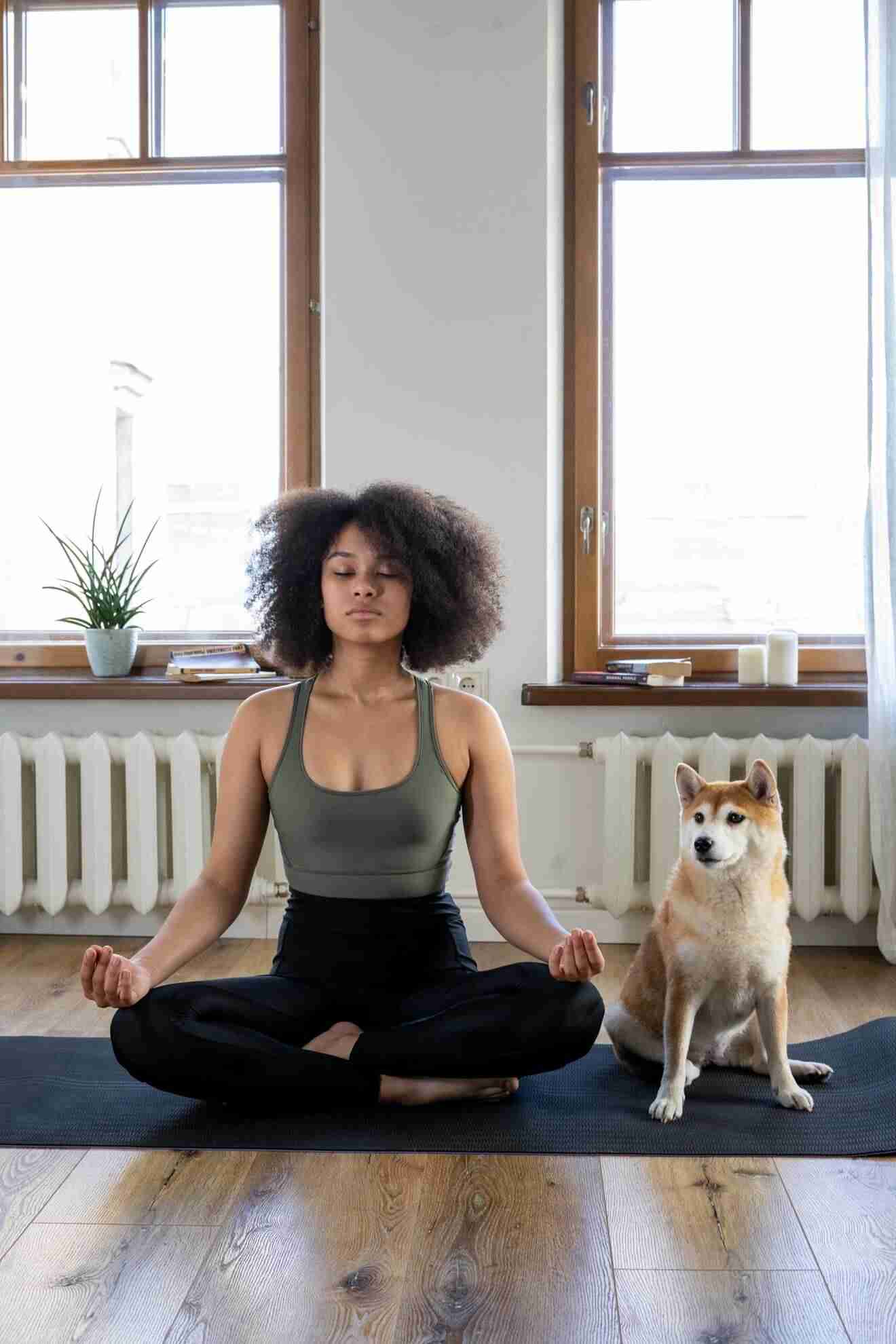 Woman meditating besides a dog