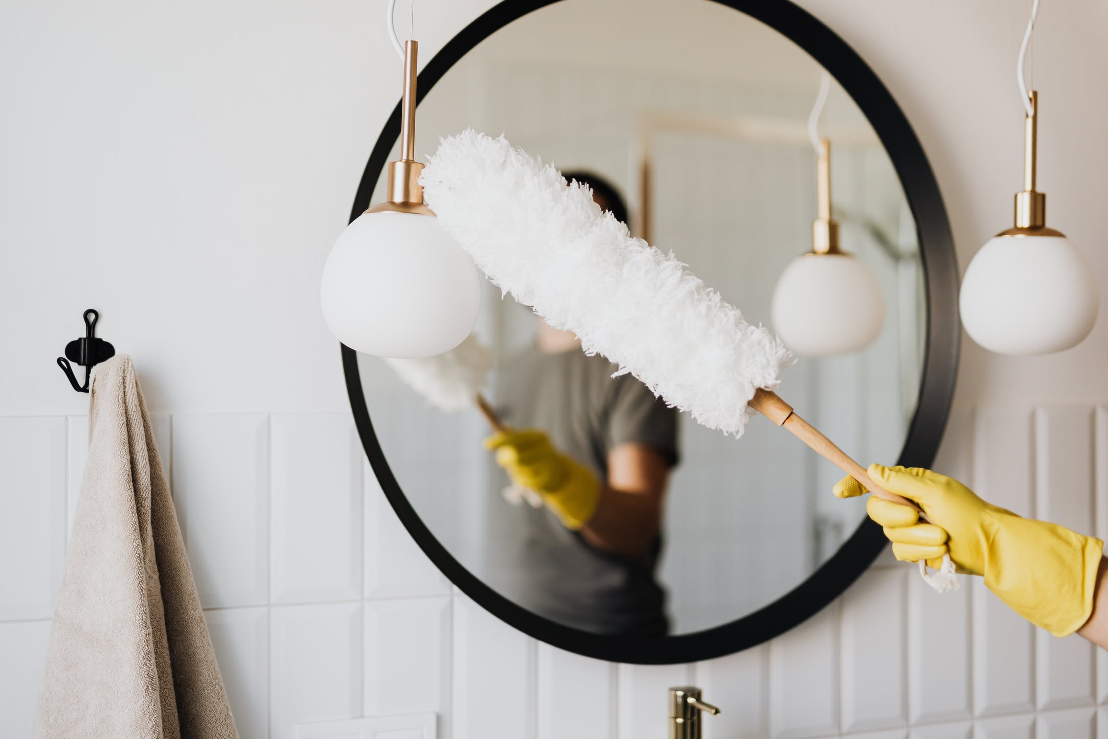 A man cleaning the light fixture in a house.